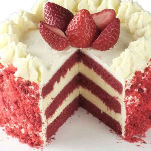 Close up of handcrafted luxury red velvet cake topped with strawberries