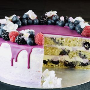 Slice cut out of handcrafted Lemon and Blueberry celebration cake with drip topping