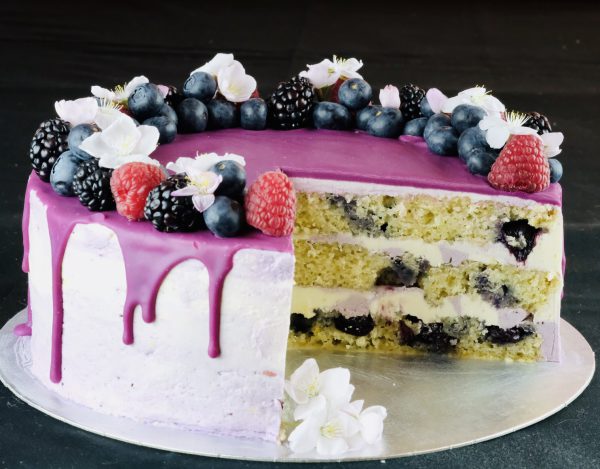 Slice cut out of handcrafted Lemon and Blueberry celebration cake with drip topping