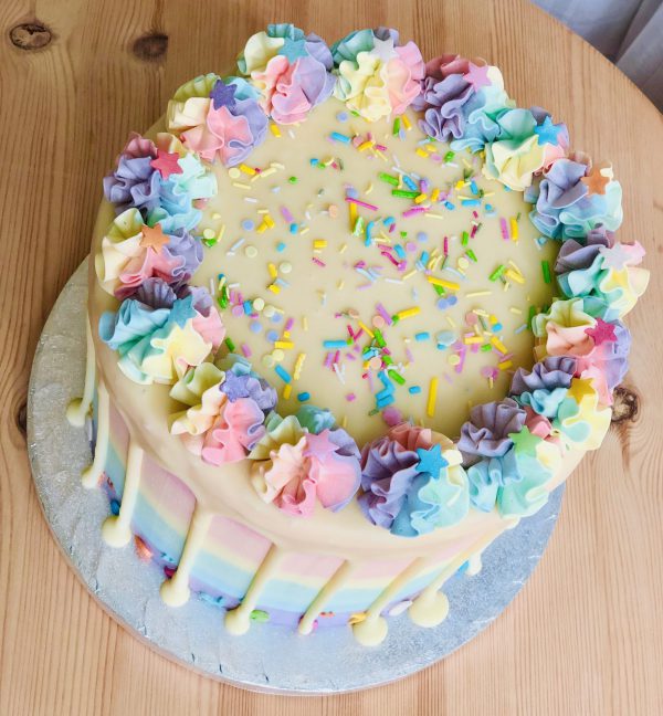 Top of bright, colourful rainbow pinata drip cake