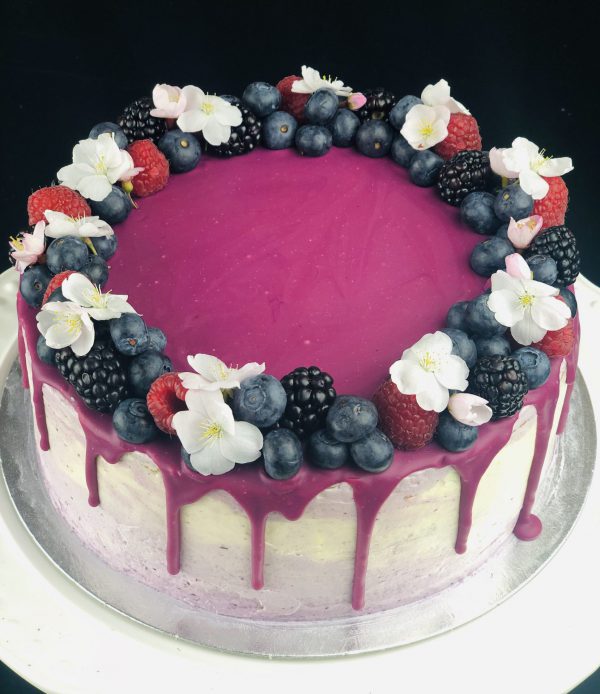 Top of Lemon and Blueberry celebration cake with fruit and flower decoration.