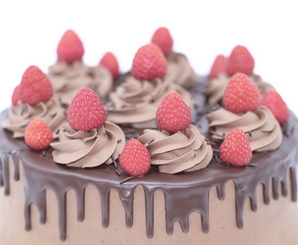 Close up of gourmet chocolate celebration cake with chocolate icing and strawberry topping