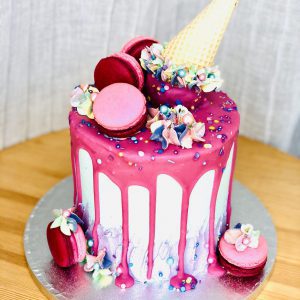 Extravagant luxury pink birthday cake with macarons and ice cream cone topping