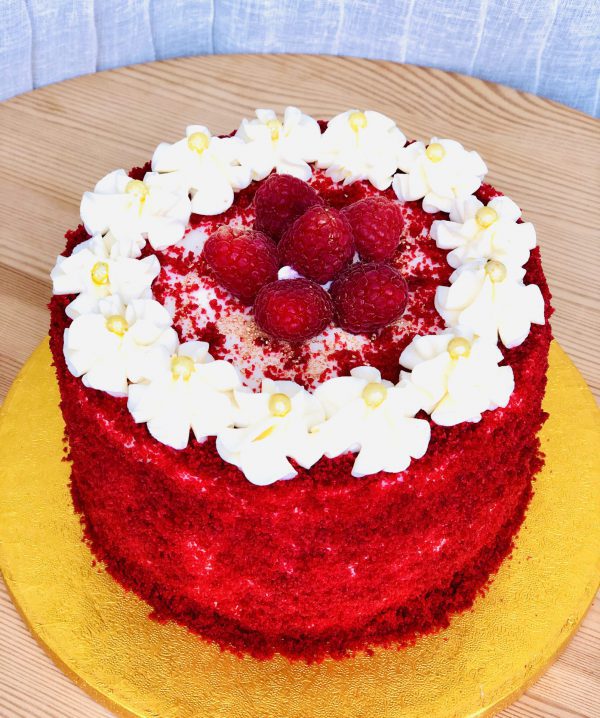 Gourmet red velvet celebration cake topped with fresh strawberries and icing flowers