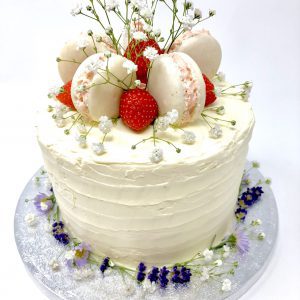 Handcrafted luxury celebration cake with fresh strawberries and freshly baked French macarons on top