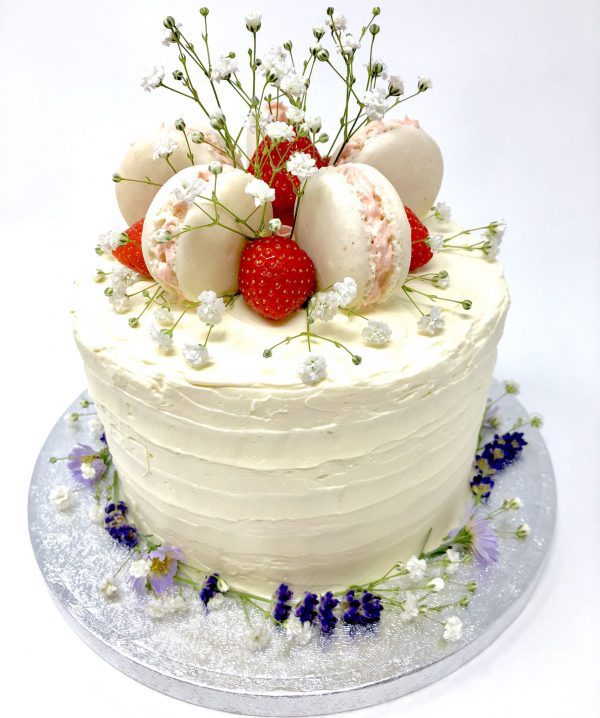 Handcrafted luxury celebration cake with fresh strawberries and freshly baked French macarons on top