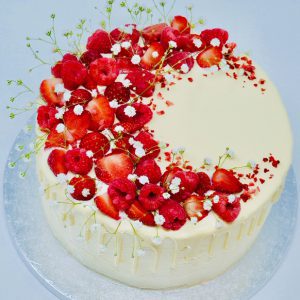 Beautiful handcrafted strawberry, raspberry and lemon drip cake topped with strawberries and raspberries