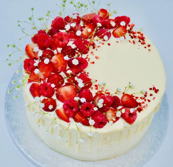 Beautiful handcrafted strawberry, raspberry and lemon drip cake topped with strawberries and raspberries