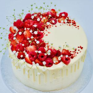 Gourmet strawberry, raspberry and lemon cake decorated with fresh fruits and flowers