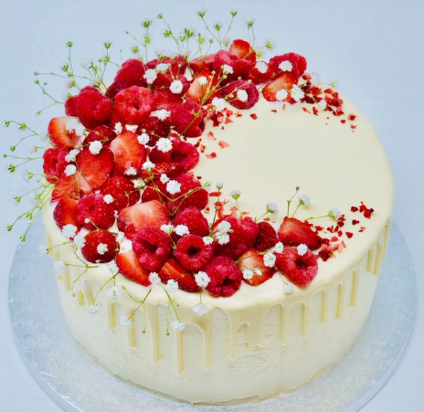 Gourmet strawberry, raspberry and lemon cake decorated with fresh fruits and flowers