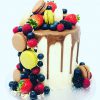 Unique French fruit macaronia cake with chocolate drip and covered with macarons and berries