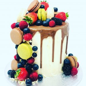 Unique French fruit macaronia cake with chocolate drip and covered with macarons and berries