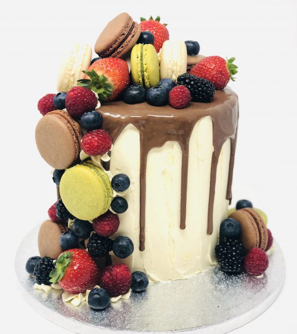 Handcrafted French fruit macaronia drip cake, topped with freshly baked macarons and fruits