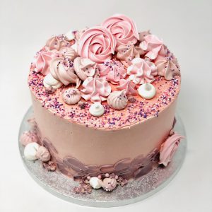 Gourmet bespoke pink celebration cake with freshly baked pink meringue kisses