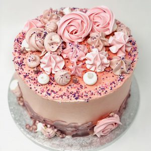Handmade bespoke pink celebration cake with freshly baked pink meringue kisses and swirls