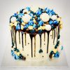 Bespoke gourmet celebration cake with blue and gold ganache drip and handmade macarons and meringues