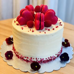 Handcrafted raspberry and vanilla sponge cake topped with pink macarons