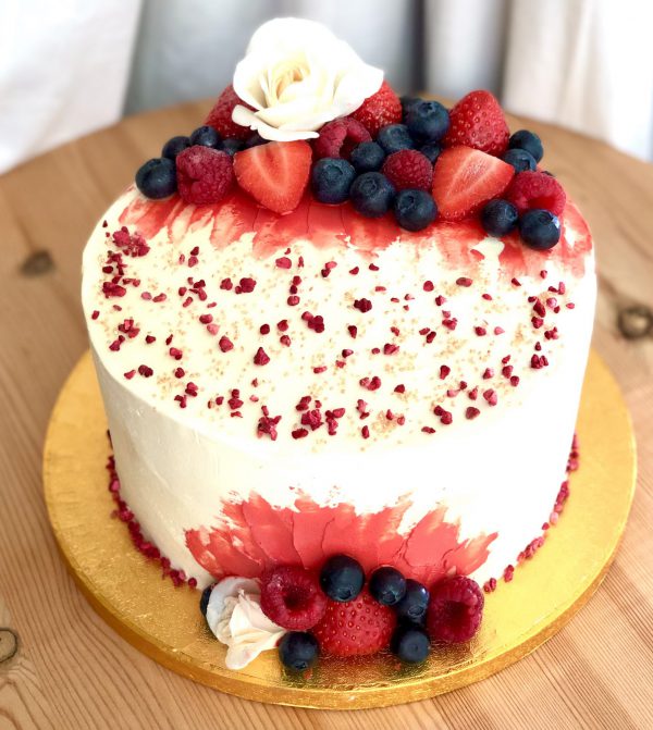 Elegant strawberry and vanilla celebration cake with fresh flowers and berries