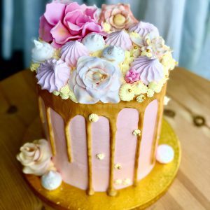 Showstopping handcrafted pink and gold birthday cake with pink meringues and gold ganache drip