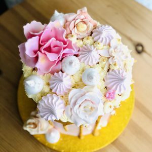 Pink flower meringues and French buttercream on handmade pink and gold drip cake