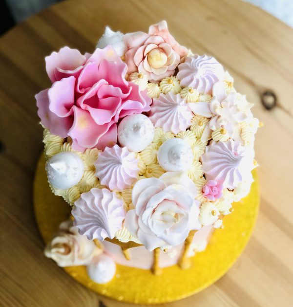 Pink flower meringues and French buttercream on handmade pink and gold drip cake