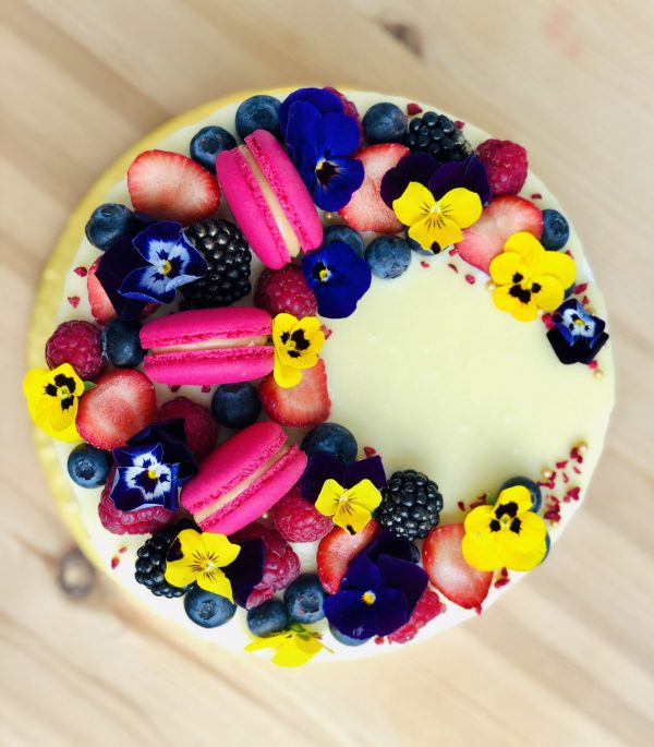 Colourful handmade berry birthday cake topped with French macarons