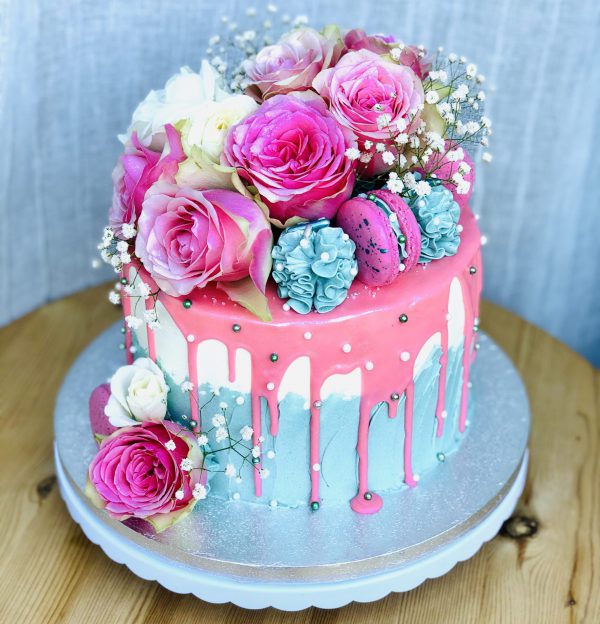 Luxury pink and blue handmade birthday cake with fresh pink and blue flowers and macarons
