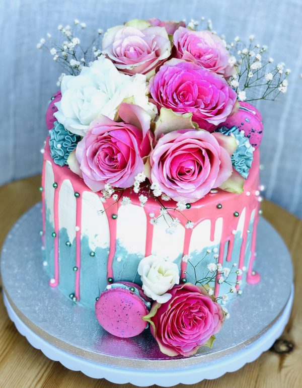 Stunning pink, blue and white gourmet birthday cake with fresh pink flowers and pink macarons